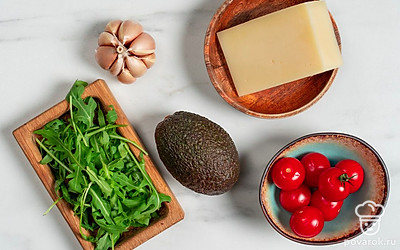 Вымойте и обсушите авокадо, помидоры черри и руколу. Помойте и почистите чеснок. Разрежьте авокадо пополам и удалите косточку. Приготовьте блендер с чашей, терку, шпажки для канапе и блюдо для подачи.