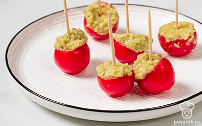 Перебейте и смешайте содержимое чаши до консистенции однородного крема. Разложите получившийся крем по полым помидорам. Воткните в закуску шпажки для канапе и переложите на сервировочное блюдо.