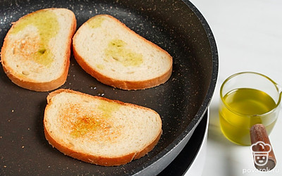 Разогрейте сухую сковороду на огне чуть выше среднего. Обжарьте на ней ломтики батона с двух сторон до золотистого цвета. Сбрызните хлеб 1 ч.л. оливкового масла, переложите хлеб на блюдо.