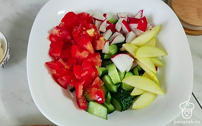 Тонкими слайсами нарежьте яблоко, добавьте к овощам.