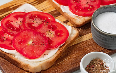 Нарежьте помидор кружочками. На ломтики хлеба намажьте плавленый сыр. Сверху уложите кружочки помидоров. Посолите по вкусу и посыпьте смесью перцев.