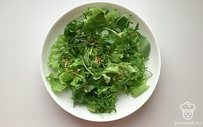 На блюдо выложить листья салата и рукколу, посолить и полить половиной заливки. Перемешать.