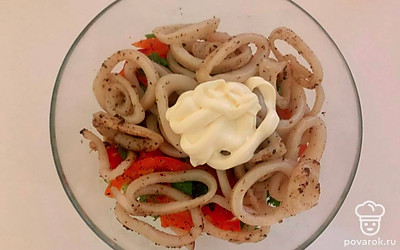 В миску к овощам добавьте специи и обжаренные кольца кальмаров. Заправьте салат постным майонезом и хорошо все перемешайте. Дайте настояться 7 минут.