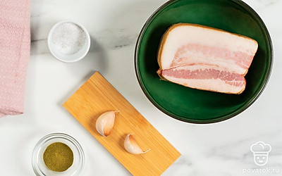 Разморозьте, помойте и обсушите сало. Помойте и почистите чеснок. Разогрейте духовку до 180 градусов. Подготовьте фольгу и небольшую форму для запекания.