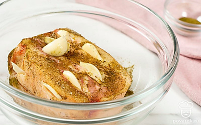 Натрите кусок сала солью и специями. Нарежьте чеснок тонкими пластинками. В сале острым ножом сделайте глубокие надрезы, поместите в них чеснок.