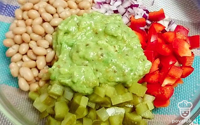 Добавьте к овощам заправку из авокадо и перемешайте.