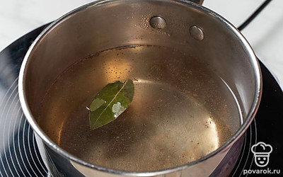 Налейте в сотейник воду, добавьте соль, перец и лавровый лист. Поставьте на сильный огонь и доведите маринад до кипения. После этого сразу снимите его с огня и полностью остудите. 