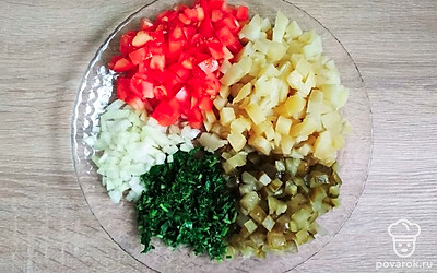 Нарежьте мелким кубиком маринованные огурцы. Очистите лук и мелко порежьте. Измельчите зелень. Мелко нарежьте помидоры.