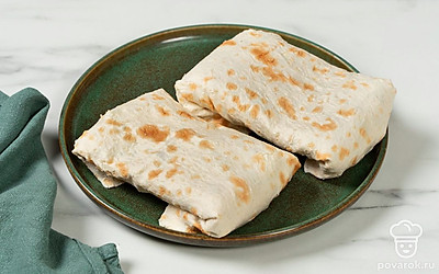 Аккуратно сверните лаваши с начинкой в конвертики или роллы. Выложите закуску на тарелку и уберите в холодильник на 20-30 минут перед подачей.