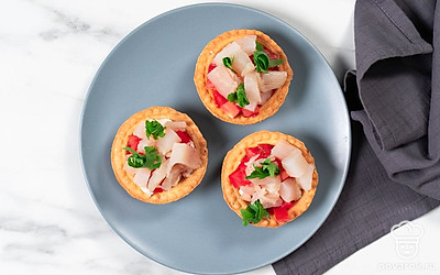 Украсьте готовые тарталетки с рыбой свернутыми в колечко листочками рукколы.