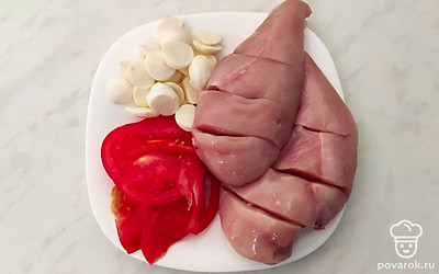 Нарежьте помидоры и сыр моцарелла тонкими слайсами. На куриной грудке сделайте поперечные глубокие разрезы практически насквозь, их должно быть как минимум 3 на каждой грудке.