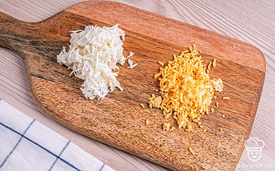 Снимите с яиц скорлупу, разделите белки и желтки. Сначала потрите на мелкой терке белки, затем желтки, разместив натертое в разные мисочки.