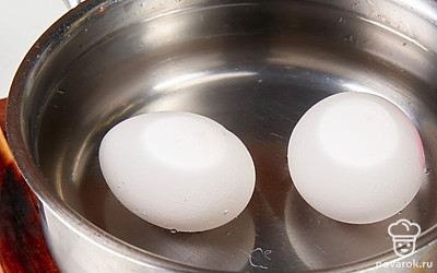 Выложите яйца в сотейник, залейте водой. Поставьте на сильный огонь. Как только вода закипит, приоткройте крышку и варите до готовности яиц 5-7 минут. Затем остудите их, почистите и натрите на мелкой терке.