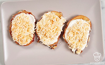 Смажьте каждый ломтик хлеба с одной стороны майонезно-чесночным соусом, а сверху посыпьте их измельченными яйцами. Выложите гренки натарелку для подачи. 