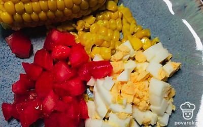 Яйца отварите до готовности, очистите и нарежьте на кубики. Отварную кукурузу разделите на зерна. Помидор нарежьте кубиком.