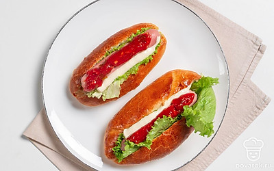 Сделайте небольшой надрез в булочках. Поместите внутрь листья салата и сосиски. А также не забудьте полить хот-доги любимыми соусами. Это может быть кетчуп, майонез, горчица или все сразу. 