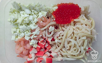 Креветки и кальмар отварите в подсоленной воде. Отдельно отварите яйца вкрутую, а затем очистите от кожуры и нарежьте. Нарежьте крабовые палочки и кальмары, а креветки очистите. В емкость выложите креветки и кальмары. Добавьте в салат икру и заправьте его майонезом.