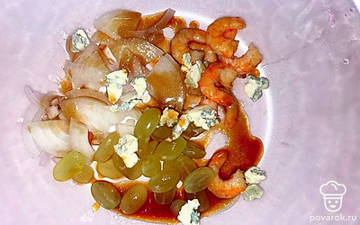 Креветки очистите. Чеснок измельчите. Репчатый лук нарежьте полукольцами, виноград - пополам. Обжарьте чеснок на сливочном масле, а затем добавьте креветки и обжаривайте 3 минуты. Листья салата выложите в тарелку, на них положите креветки, лук и виноград в салатник. Добавьте поломанный на кусочки дорблю. Для соуса смешайте мед, масло и соус. Салат посолите, поперчите и заправьте соусом. Перед подачей украсьте красной икрой.