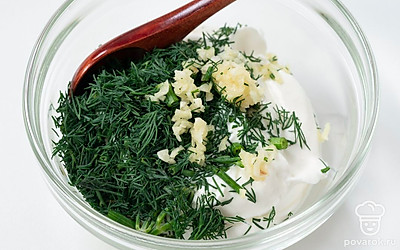 Добавьте измельченный чеснок и зелень в сметану, перемешайте до однородности.