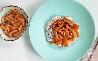 Выложите из банки маринованные грибы. Если грибы крупные, нарежьте их ломтиками. Распределите их поверх курицы.