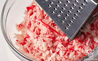 Натрите крабовые палочки на мелкой терке.