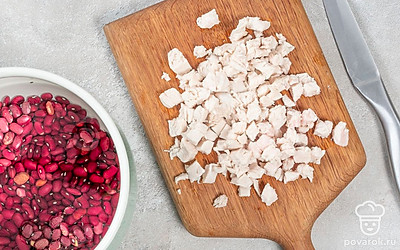 Начните приготовление. Фасоль промойте, залейте водой и поместите на небольшой огонь. Дождитесь кипения, убавьте огонь и оставьте фасоль вариться на 1 час до полной готовности. Куриное филе нарежьте небольшими кусочками или порвите руками.