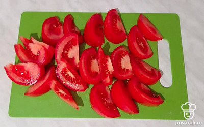 Готовую печень остудите и переложите в большую миску. Тонкими полукольцами нарежьте лук. Не очень мелко порубите ножом грецкие орехи. Помидоры порежьте крупными дольками. Чеснок натрите на мелкой терке. Мелко порубите кинзу и петрушку.