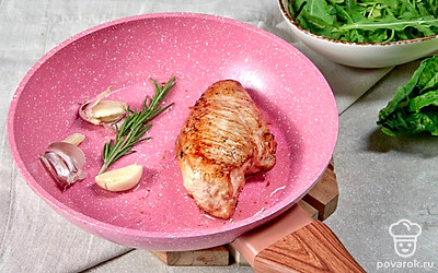 Приготовьте куриное филе. Посыпьте мясо солью и перцем, смажьте небольшим количеством растительного масла. Возьмите неочищенный зубчик чеснока и раздавите его при помощи ножа. Поставьте на огонь сковороду, добавьте оставшееся растительное масло. Отправьте на нее мясо, ветку розмарина и чеснок. Через минуту уберите розмарин и чеснок. Грудку обжарьте до появления золотистого цвета, накройте крышкой, сделайте меньше огонь и потомите минут 7. Дайте грудке остыть и нарежьте ее слайсами.