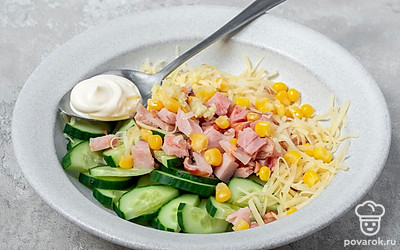 Приготовьте салат. В миску для салата выложите копченое куриное мясо, нарезанный огурец, кукурузу, тертый сыр. Добавьте майонез, чеснок и соль. Тщательно перемешайте.