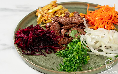 Выложите мясо в центр блюда для подачи. Затем вокруг говядины выложите остальные ингредиенты: лук, корейскую морковку, свеклу, картошку, зелень. По виду они должны напоминать разноцветные лепестки. 