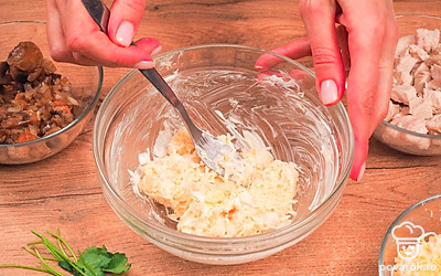 Подготовьте оставшиеся продукты. Отваренные яйца и сыр натрите на терке. К сыру в отдельной миске добавьте майонез и чеснок, перемешайте. Грецкие орехи измельчите до состояния крошки.