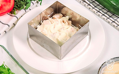 Теперь соберите салат. Для этого возьмите специальную форму, плоский салатник или форму для запекания. Выложите на дно нарезанную курицу и смажьте майонезом.