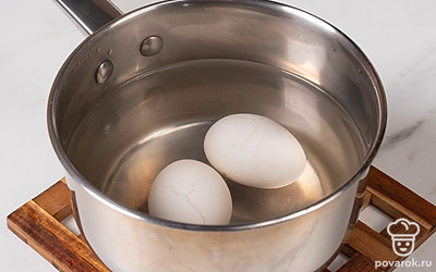 В сотейник выложите яйца и влейте воду, отварите яйца вкрутую. Затем остудите их под ледяной водой и почистите.
