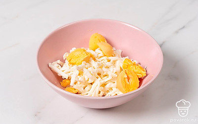 Плавленый сырок натрите на крупной терке. Яйца разрежьте пополам вдоль и аккуратно достаньте желтки. Смешайте желтки с сыром.