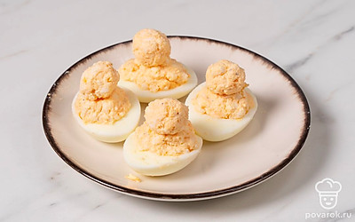 Готовой начинкой наполните половинки яиц. Из остатков начинки сформируйте небольшие шарики и прикрепите их к основе — это будет голова «цыпленка».