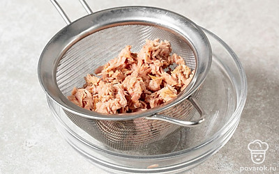 Извлеките из тунца из банки и слейте лишнюю жидкость. Разделите консервы на волокна.