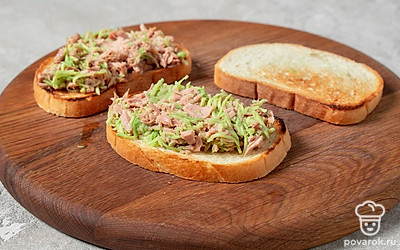 Выложите немного готовой начинки на тосты и распределите ее по всей поверхности.