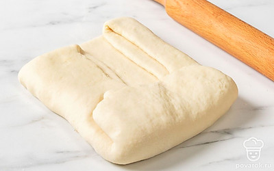 Пригните к центру прямоугольника сторону без масла. Затем сложите противоположную сторону с маслом поверх первой. Получится конверт или тонкий рулет из трех слоев. Снова раскатайте тесто в прямоугольник.