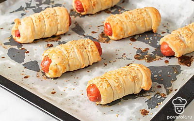 Поставьте блюдо запекаться на 20 минут. Когда сосиски в тесте зарумянятся, вынимайте противень. Остудите выпечку. 