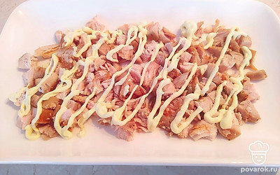 Выложите нарезанное куриное филе и покройте сеточкой из майонеза.