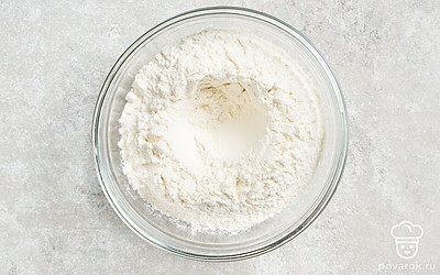 Просеянную муку пересыпьте в миску для замешивания теста и сделайте в ней углубление.