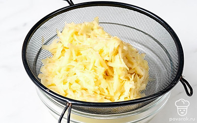 Натрите картофель на терке со средними отверстиями, выложите его в дуршлаг. Поставьте дуршлаг на миску и дайте картофелю постоять около 30 минут, пока с него не уйдет лишний сок.