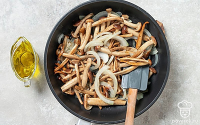 Выложите к луку опята, перемешайте, немного прибавьте огонь. Обжарьте все вместе в течение 7 минут, пока грибы не начнут выделять сок.