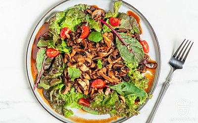 На тарелке разложите салатные листья. Сверху выложите ароматные шампиньоны в соевом соусе. Посыпьте закуску семенами кунжута и подайте на стол.