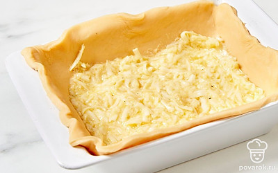 В форму для запекания положите первый большой пласт теста так, чтобы его края образовали бортики пирога. На него равномерно выложите одну часть начинки.
