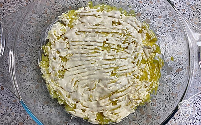 Картофель натираем на крупной терке. Выкладываем нижним слоем в форму для салата. Немного солим и смазываем майонезом.