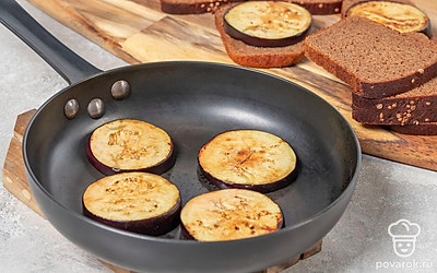 Поставьте сковороду на огонь, влейте масло, дайте хорошенько разогреться. Переложите баклажаны в сковороду и обжарьте по 2-3 минуты с каждой стороны до аппетитной румяности. Выложите по одному баклажану на каждый кусочек хлеба.