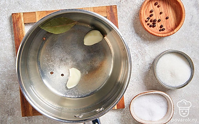 Когда вода начнет кипеть, влейте уксус и добавьте чеснок, лавровый лист и специи. Хорошо перемешайте маринад.