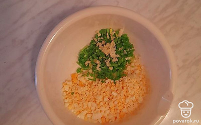 Мелко нарежьте яйца и зелёный лук, чеснок пропустите через пресс.