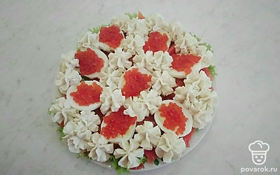 Между яйцами, при помощи мешка, сформируйте цветы, на яйца выложите по одной чайной ложке красной икры.